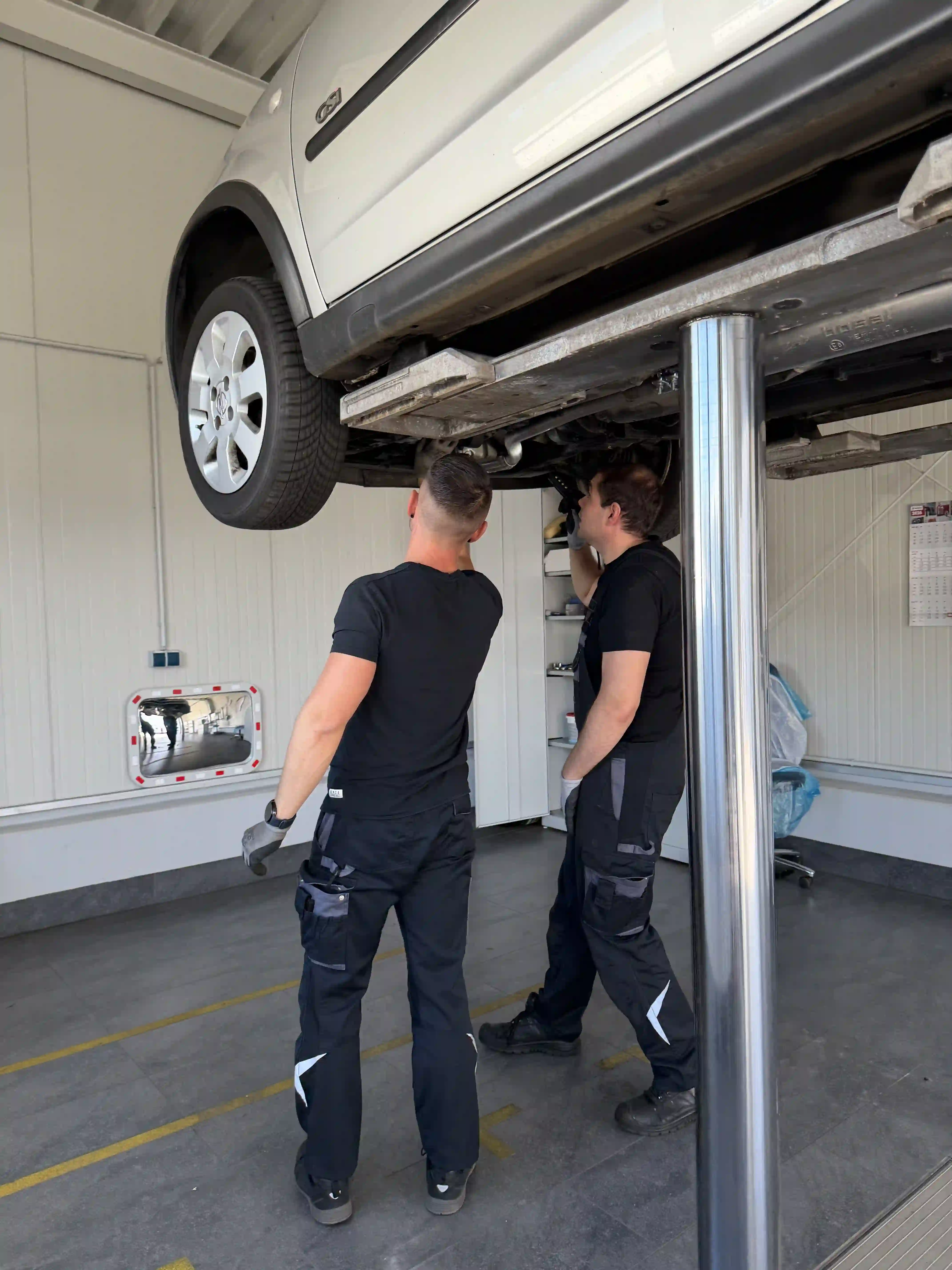 Zwei Mechaniker arbeiten an einem Fahrzeug auf der Hebebühne
