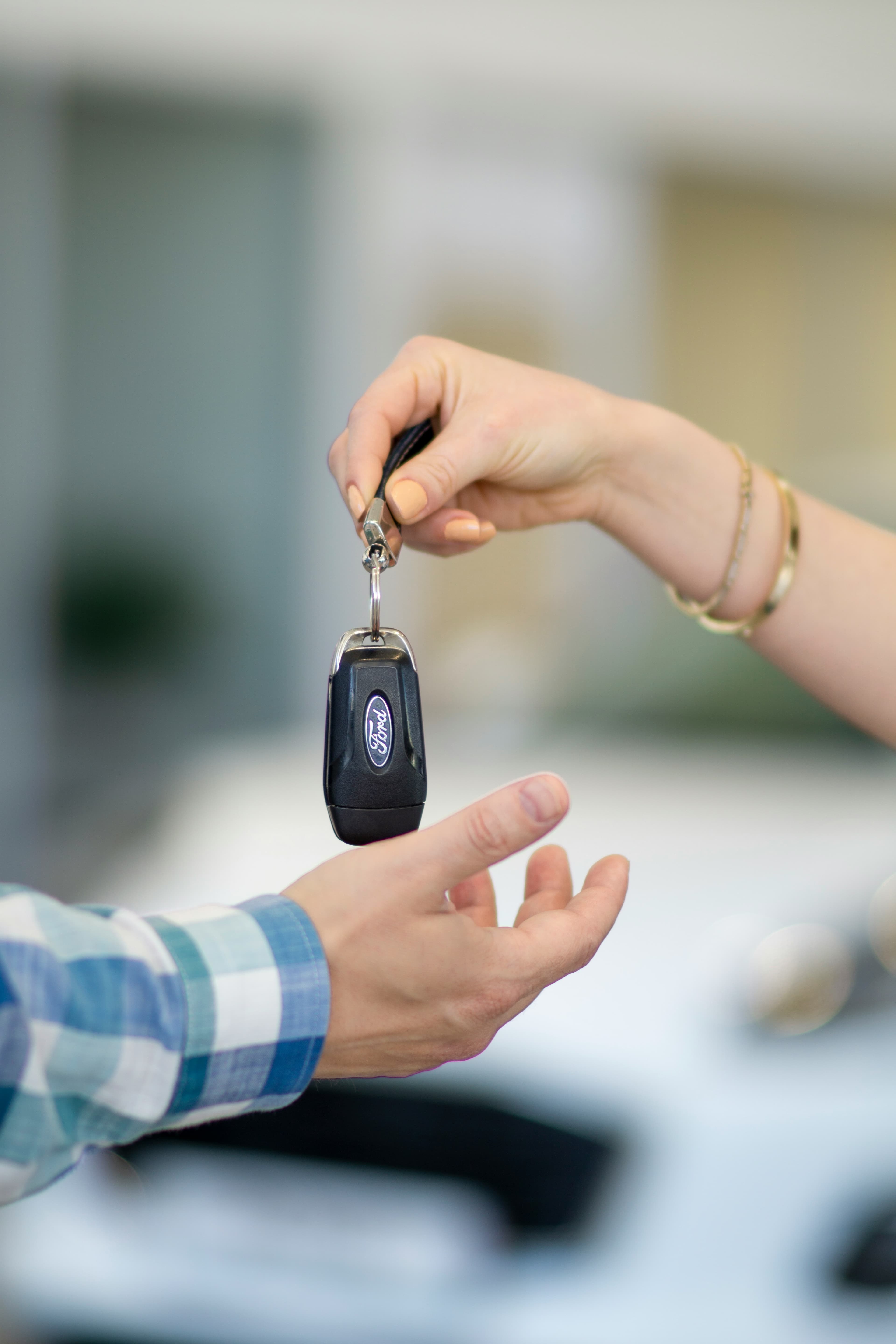 Schlüsselübergabe: eine Hand reicht einen Autoschlüssel in die geöffnete Hand des Käufers.